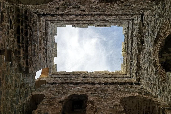 Looking straight up from inside a ruined stone tower towards the sky.