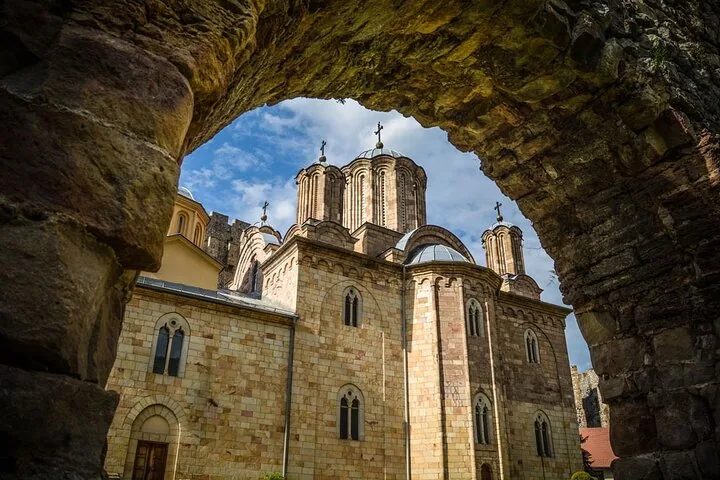Ein altes Kloster aus Stein mit Kuppeln, eingerahmt von einem Steinbogen.
